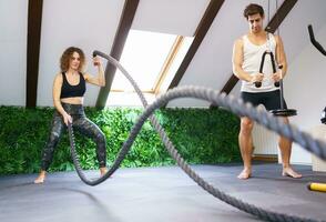 Strong sportswoman exercising with battle ropes during training photo