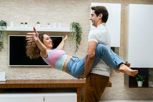 Joyful couple embracing against TV and potted plants at home photo