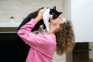 Unrecognizable woman raising up and kissing cute cat photo