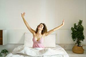Cheerful woman sitting on bed in sleepwear photo