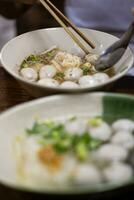 cerca arriba de blanco arroz fideos, claro sopa, carne pelotas con ingredientes en blanco bol. foto