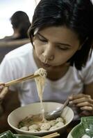 cerca arriba de mujer comiendo fideos en blanco bol. foto