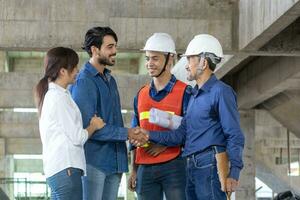 Newly wed couple is handshaking with engineering contractor at their under construction house to inspect building progress and quality control for home ownership and real estate development photo