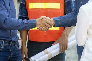 Newly wed couple is handshaking with engineering contractor at their under construction house to inspect building progress and quality control for home ownership and real estate development photo