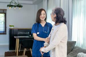 Senior woman get medical service visit from caregiver nurse at home while practice using walking cane or stick after knee surgery photo