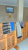 sarongs and prayer mats hanging from the curtain dividing the mosque photo