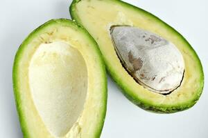 Avocado fruit cut in half on a white background. Green fruits are for vegetarians. Delicious diet food. photo