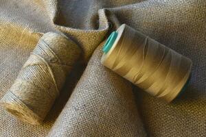 Skeins of thread on crumpled burlap. Yellow threads on coarse cloth. The material for the bags. photo