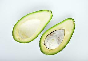 Avocado fruit cut in half on a white background. Green fruits are for vegetarians. Delicious diet food. photo