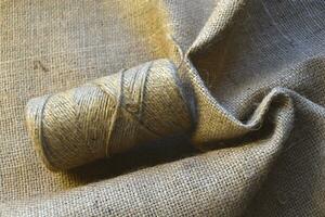 Skeins of thread on crumpled burlap. Yellow threads on coarse cloth. The material for the bags. photo