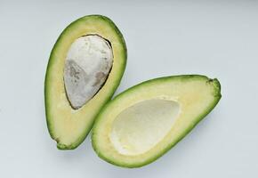 Avocado fruit cut in half on a white background. Green fruits are for vegetarians. Delicious diet food. photo