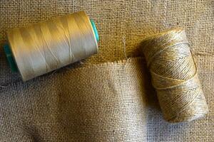 Skeins of thread on crumpled burlap. Yellow threads on coarse cloth. The material for the bags. photo