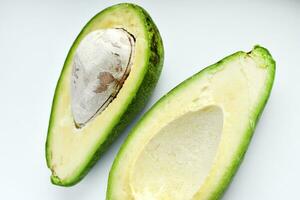 Avocado fruit cut in half on a white background. Green fruits are for vegetarians. Delicious diet food. photo