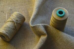 Skeins of thread on crumpled burlap. Yellow threads on coarse cloth. The material for the bags. photo