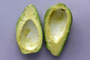 Peeled avocado fruit on a white background. Green fruits are for vegetarians. Delicious diet food. photo