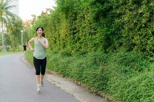 Fit Asian young woman jogging in park smiling happy running and enjoying a healthy outdoor lifestyle. Female jogger. Fitness runner girl in public park. healthy lifestyle and wellness being concept photo