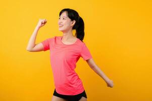 Portrait beautiful young asian sports fitness woman happy smile wearing pink sportswear posing exercise training workout isolated on yellow studio background. wellbeing and healthy lifestyle concept. photo