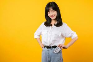 Captivating image of Asian young woman wearing white shirt and denim jeans, confidently holding cash from her shirt pocket. Fashion meets financial empowerment. Perfect for finance and fashion themes. photo