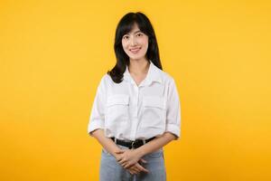 Pretty businesswoman. asian woman enterpriser happy smile wearing white shirt and denim plants with confident and smart looking isolation on yellow background. advertising product and service concept. photo