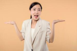 Studio portrait of happy successful confident young asian business woman. Beautiful young lady in white jacket smiling at camera standing isolated on solid beige colour copyspace background photo