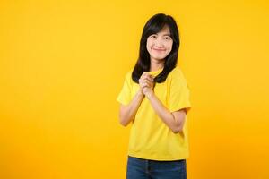 Captivating Portrait of a Young Asian Woman with Hands on Chest - Yellow Studio Background photo