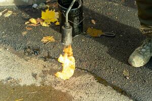 profesional asfalto grieta sellando con masilla y ardiente gas quemador método foto