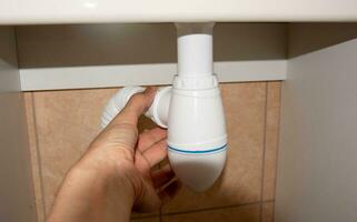 Plumber Installing Drain Siphon Under Bathroom Sink for Proper Water Drainage photo