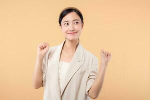 Studio portrait of happy successful confident young asian business woman. Beautiful young lady in white jacket smiling at camera standing isolated on solid beige colour copyspace background photo