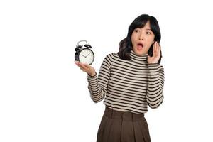 retrato de emocionado joven asiático mujer con suéter camisa participación alarma reloj aislado en blanco antecedentes foto