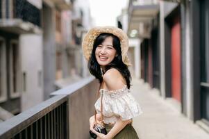 Happy youth asian woman with camera travels street city trip on leisure weekend. Young hipster female tourist sightseeing summer urban Bangkok destination. Asia summer tourism concept. photo