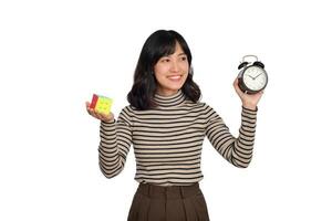 Asian woman holding alarm clock and puzzle cube standing on white background. solving cubic problems, problem solution and making strategic moves concept photo