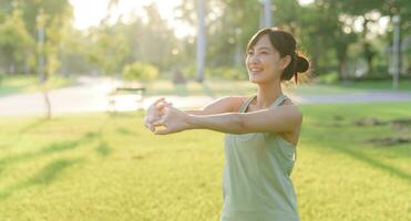 Female jogger. Fit young Asian woman with green sportswear stretching muscle in park before running and enjoying a healthy outdoor. Fitness runner girl in public park. Wellness being concept photo