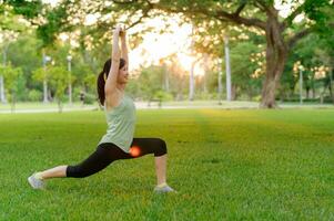 Female jogger. Fit young Asian woman with green sportswear stretching muscle in park before running and enjoying a healthy outdoor. Fitness runner girl in public park. Wellness being concept photo