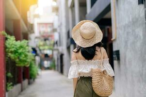 Happy youth asian woman with camera travels street city trip on leisure weekend. Young hipster female tourist sightseeing summer urban Bangkok destination. Asia summer tourism concept. photo