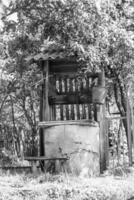 Old well with iron bucket on long forged chain for clean drinking water photo