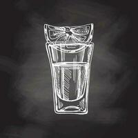 Hand-drawn shot glass with tequila with a slice of lime on chalkboard background. Design element for the menu of bars. Vector sketch illustration in engraving style. Mexican, Latin America.