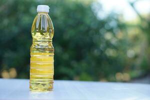 Bottle of vegetable oil for cooking. Outdoor background. Extracted from seeds or from other parts of plants, such as sunflower seeds, soy beans, olive, palm fruits. photo