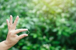 Close up hand hold silver ring, outdoor background. Concept, accessory, jewelry. Ring is the symbol or classic representation of love, engagement and wedding. photo