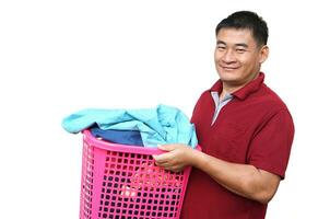 Asian man holds laundry basket full of clothes for washing, isolated on white background. concept, daily chores, household. Real life duty routine, washing cloth for hygine. photo