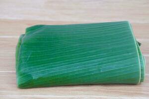 Folded banana leaves for food wrapping on brown wooden background. Concept, package container from nature, safe for wrapping food. Eco friendly and safety for consumers. photo