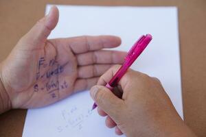 Palm with written physics formula on it during doing writing examination on paper by pen. Concept, cheat the test, Dishonest behaviour. Education assessment. photo