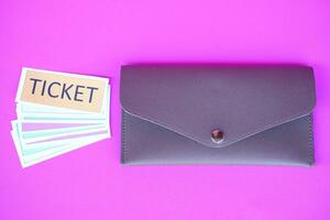 Leather envelope and pile of paper tickets. Pink background. Concept, tickets for passing or enter to join activity or public vehicles. Tickets for playing games. Teaching aids. photo