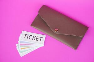 Leather envelope and pile of paper tickets. Pink background. Concept, tickets for passing or enter to join activity or public vehicles. Tickets for playing games. Teaching aids. photo