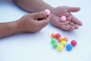 Close up man hands holds small colorful plasticine dough balls. Concept, alzheimer, weak muscle patients recovering activity by sculpting. Make concentration. Develop imagination. photo