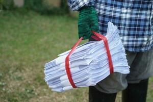 Close up man hold pile of used paper, tied with rope. Concept, sorting garbage for recycle next steps. Eco friendly activity. Waste paper management. Reduce reuse, recycle paper. photo