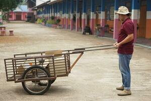 Asian man janitor is carrying wheel cart to keep garbage in school. Concept, service occupation. Clean keeper for good environment. Collector garbage photo