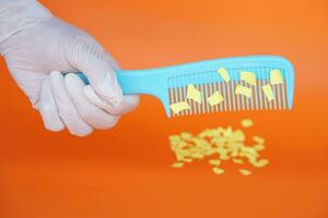 Comb and small pieces of paper. Equipment, prepared to do experiment about static electricity. Orange background. Concept, Science lesson, fun and easy experiment. Education. Teaching aids. photo