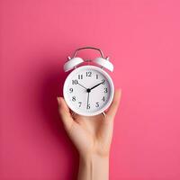 AI generated Hand Holding a Classic White Alarm Clock on Pink Background photo