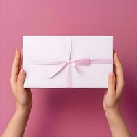 AI generated Hands Holding a Gift Box with Pink Ribbon on Pink Background photo