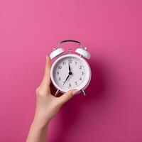 AI generated Hand Holding a Classic White Alarm Clock on Pink Background photo